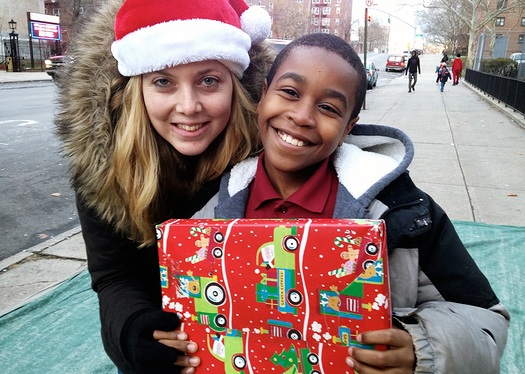 Monelle New Yorkin kyhlle lapselle Metro World Childin antama joululahja on ainoa, jonka he saavat. Kuvassa yksi onnellisista paketin saajista jrjestn pyhkoulutyntekijn kanssa. Kuva: Metro World Child